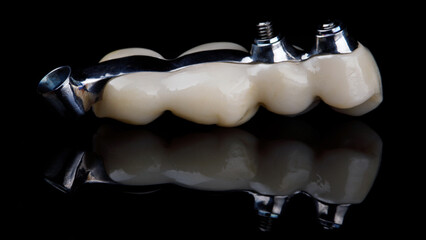 titanium dental beam in a zircon prosthesis on a black background with reflection