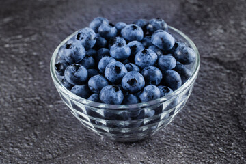 Blueberries organic natural berry on dark background. Blueberry in glass bowl plate.