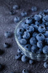 Blueberry in glass bowl plate. Blueberries natural organic berry with water drops on dark background.