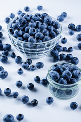 Blueberry with water drops. Blue berries in glass plate on white background. Many natural organic blueberries. Vertical photo.