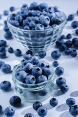 Blueberries with water drops. Blueberry in glass plate and on the table on white background. Many natural organic blueberries.