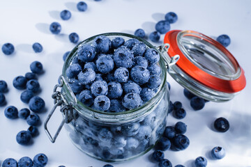 Blueberries with water drops in glass jar on white background. Blueberry summer seasonal berry. Many natural organic blueberries.