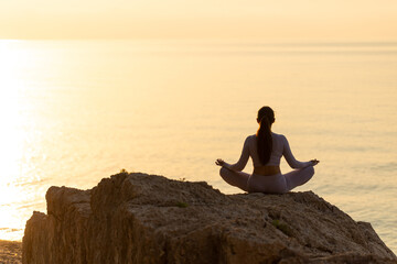 Serenity and yoga practicing at sunset, meditation. silhouette on sea background with sunrise