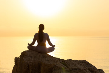 Serenity and yoga practicing at sunset, meditation. silhouette on sea background with sunrise