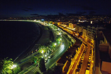 Fototapeta na wymiar Amazig View on Nice ( Promenade des Anglais ) - photo from Colline du Chateau . People walking and electric lights on - sunset in capital of french Riviera . Lights burning.