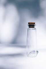 Modern apothecary concept. Empty glass miniature bottle with cork cap on contrast shadows background. Still life compositions