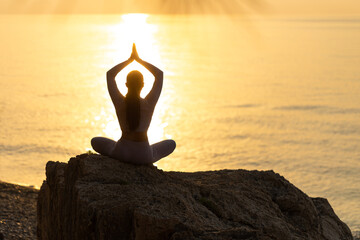 Serenity and yoga practicing at sunset, meditation. silhouette on sea background with sunrise