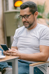 Freelance concept. Young bearded man using laptop while sitting on summer terrace