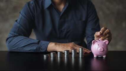 A businessman holding a coin in a piggy bank. Placing coins in a row from low to high is comparable to saving money to grow more. The concept of growing savings and saving by investing in stock funds.