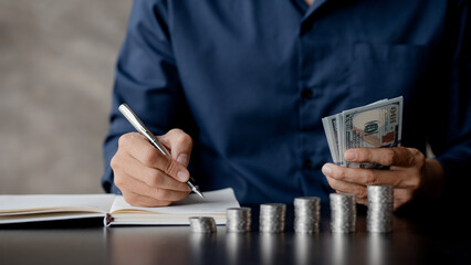 A man counting her salary to separate expenses, he keeps a monthly account for savings and investment plans, savings and investment ideas to make money grow for wealth.