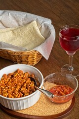 Bowl of Mexican rice and beans served with soft tortilla, salsa and glass of chilled wine cooler on wooden table top