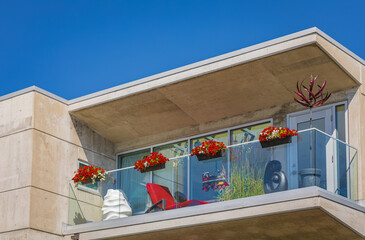 Glass balconies of modern apartment building in residential area. Balcony of modern condo with plants on sunny day