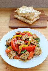 Mouthwatering vegetables salad and roasted Tempeh cubes with stack of fresh Tempeh in the backdrop