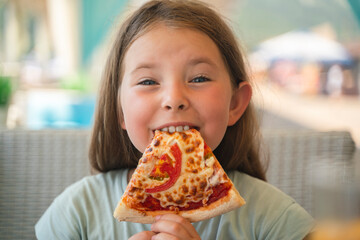 A young girl with plaits is eating a piece of pizza. High quality photo