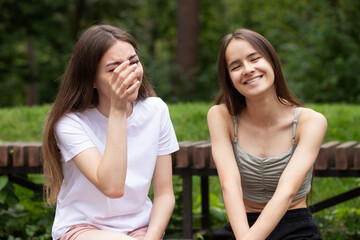 teen girls having fun, friends laugh together, young women relaxing in the park in summer