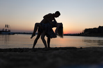 silhouettes of people on the beach at sunset. Dancing on the beach