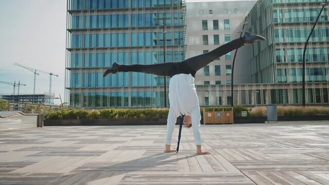 Flexible and cool businessman doing acrobatic tricks outdoor. Young business man having fun dancing while going to work.