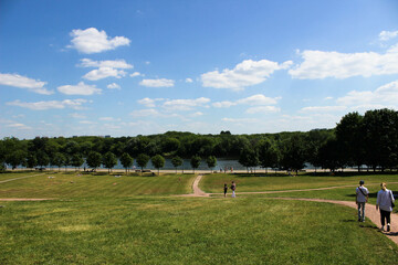 Obraz premium A path in a huge meadow with a green lawn and sunbathing people in the meadow