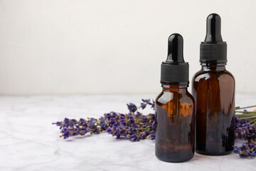 Essential oil of lavender on a white texture background. Spa concept. RELAX. Bottle with fragrant oil and lavender flowers.Aromatic oil with lavender scent.mockup of lavender essential oil.Copy space.
