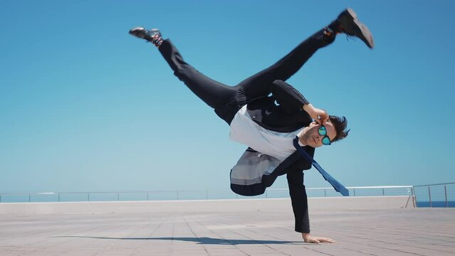 Flexible and cool businessman doing acrobatic tricks outdoor. Young business man having fun dancing while going to work.