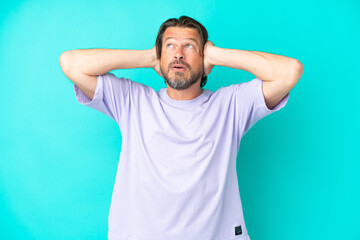 Fototapeta premium Senior dutch man isolated on blue background frustrated and covering ears