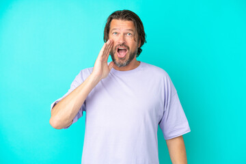 Senior dutch man isolated on blue background with surprise and shocked facial expression
