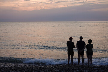 Fototapeta premium personnes devant un coucher de soleil sur la plage