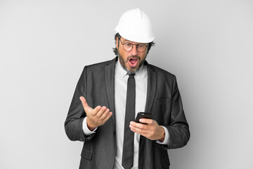 Young architect man with helmet over isolated background surprised and sending a message