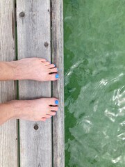 Female feet standing on a wooden dock above the sea