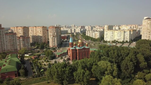 aerial panorama of the western outskirts of the microdistrict near the Kuban river, the city of Krasnodar, an Orthodox church, a Sunday school surrounded by high-rise buildings on a sunny summer day