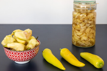 Pickled chilies in jar: mix of hungarian hot vax (on the table), blended lemon peach and aji white fantasy (in bowl).