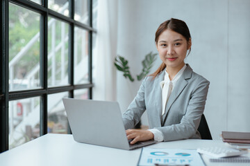 Young business women working and typing on laptop with happy and smile face on office spec.