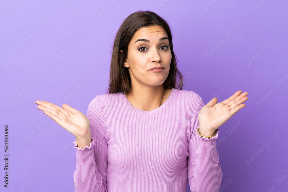 Wall mural Young caucasian woman over isolated background making doubts gesture