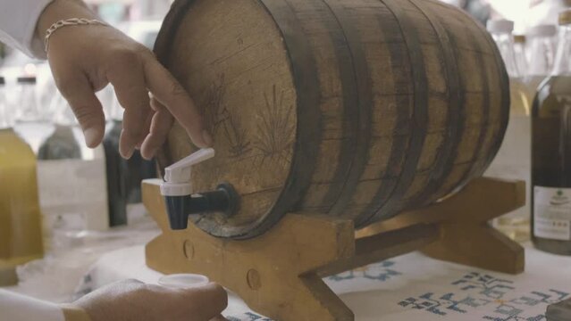 Persona sirviendo mezcal reposado de barril. Person filling reposado mezcal from the barrel.