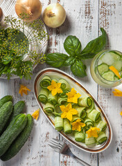 Fresh salad with cucumbers with salt and paper with ingredients and drink around. Flat lay