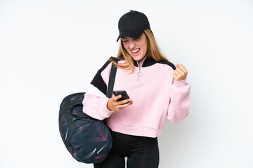 Young sport caucasian woman with sport bag isolated on white background with phone in victory position