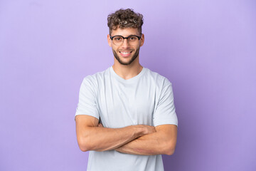 Delivery caucasian man isolated on purple background keeping the arms crossed in frontal position