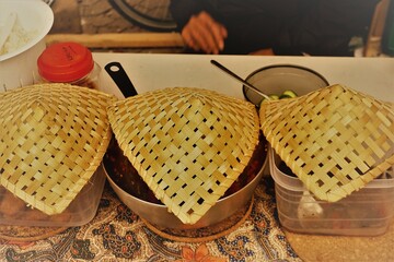 Indonesisches warmes Essen in silbernen Töpfen abgedeckt mit goldbraunen geflochtenen...