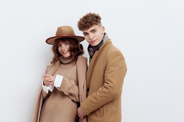 a sweet, beautiful, loving couple stands on a white background in stylish beige autumn clothes, gently embracing each other