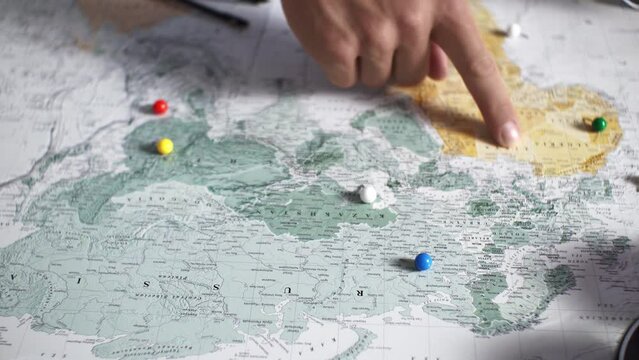 The process of choosing a travel point on the map on a summer vacation a young couple chooses a place to stay on a hot summer day, searching for a point on the maps Fingers pointing a place on the map