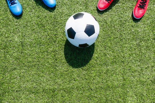 Soccer football background. Soccer ball and two pair of football sports shoes on artificial turf soccer field with shadow from football goal net on sunny day outdoors. Top view © vejaa