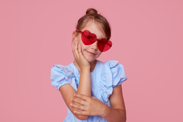 Portrait of surprised cute toddler girl in the heart shape sunglasses. Child with open mouth having...