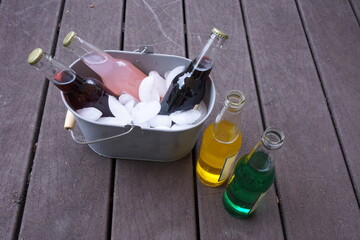 Five Colored Softdrink Bottles, Metal Tub, Wooden Deck and Ice