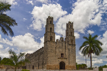 Fototapeta na wymiar Typical church of Mexico Yucatan, blue cloudy sky and palms
