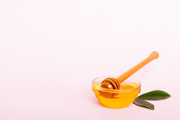 Honey in jar with leaves and honey dipper on colored background top view with copy text