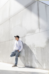 Standing Arrified to a wall a young man using a casual cap, white Hoddie jeans, lifestyle and fashion, full body