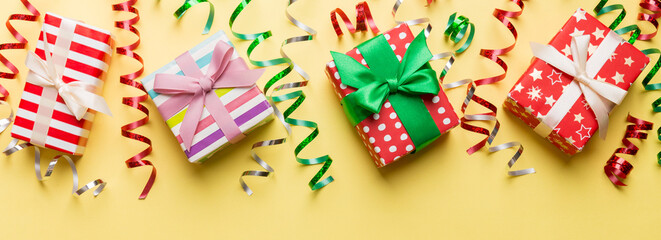 Obraz na płótnie Canvas Holiday flat lay with gift boxes wrapped in colorful paper and tied decorated with confetti on colored background. Christmas, Birthday, Valentine and sale concept, top view