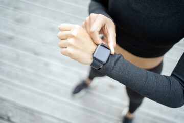 Female runner athlete does workout runs, uses fitness watch