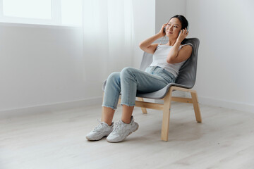 Cheerful dreaming tanned lovely young Asian woman in headphones enjoy favorite playlist looks aside at home interior living room. Sound Studio Stream Social media concept. Cool offer Banner Wide angle