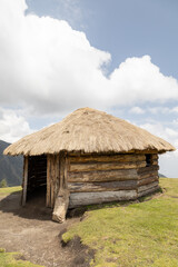 Fototapeta na wymiar rustic hut with thatched roof and wooden structure, traditional architecture in the countryside, landscape with sky and clouds on a sunny day